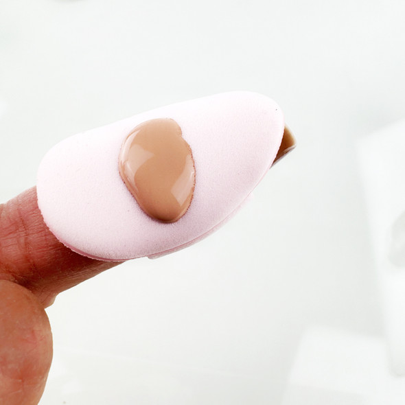 Model demonstrating the use of a mini air cushion powder puff with finger slots for precise makeup foundation application