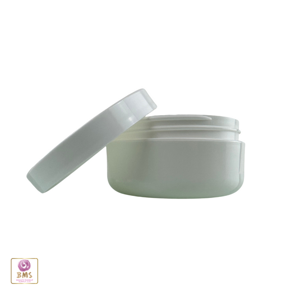 A white beauty container with the lid sitting on the side of the jar that is designed for skincare products.
