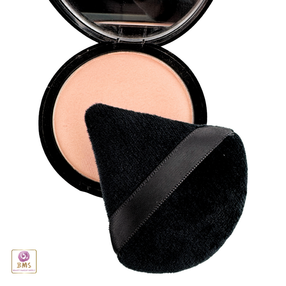A black triangle powder puff sitting on a powder compact